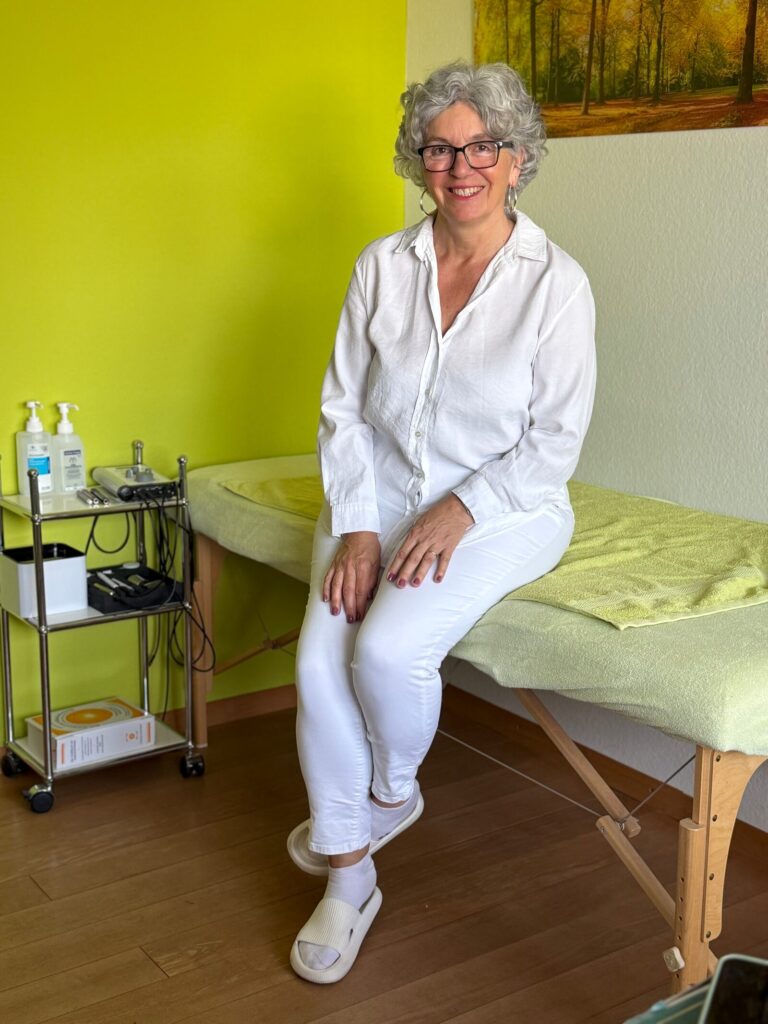 Heilpraktikerin Hiltrud Emmermann sitzt auf der Behandlungsliege ihrer Praxis in Erftstadt